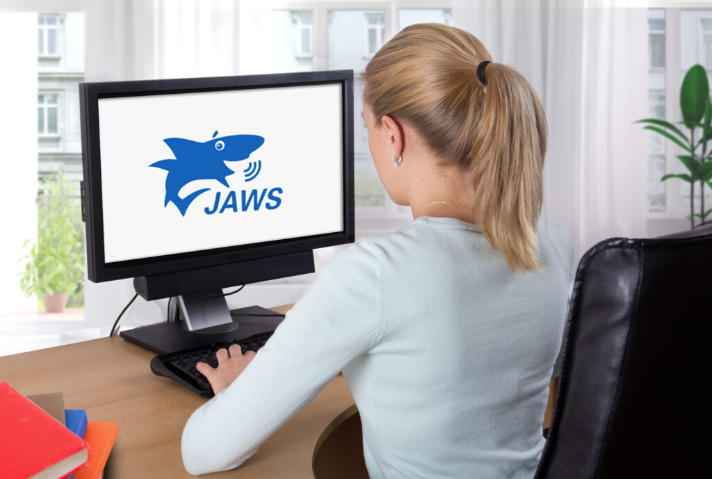 Person using a desktop computer displaying the JAWS screen reader logo, representing powerful assistive technology for blind and low-vision users