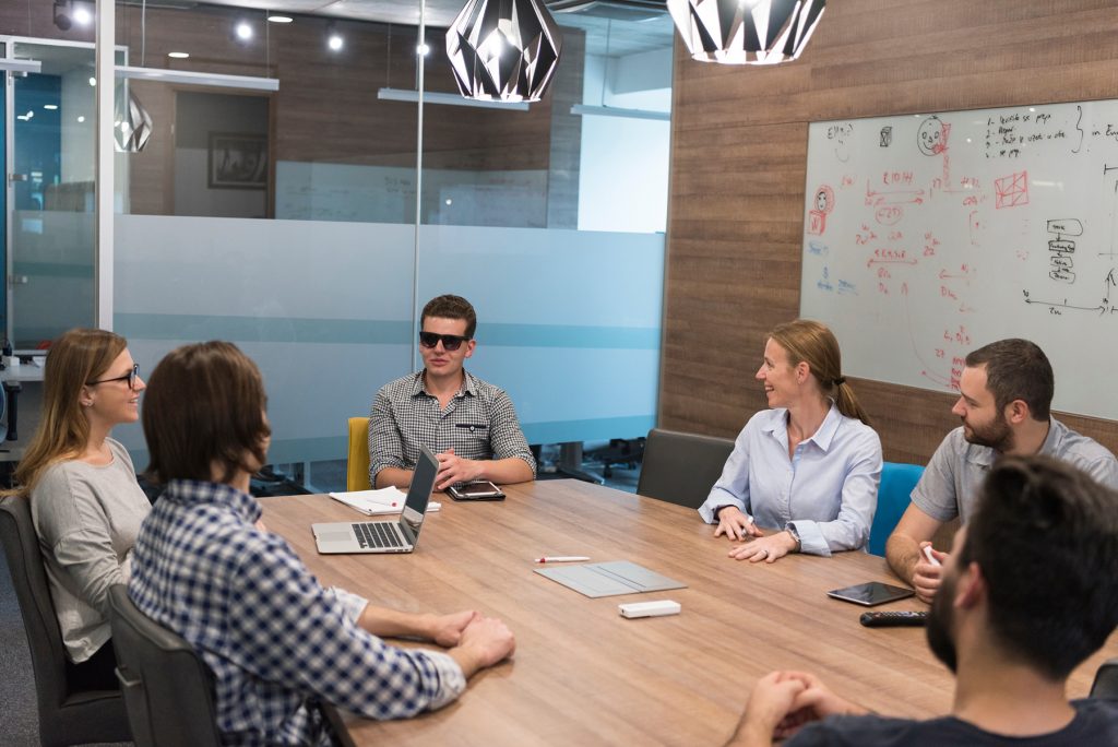 Visually impaired young business man sharing ideas in a lively project meeting.