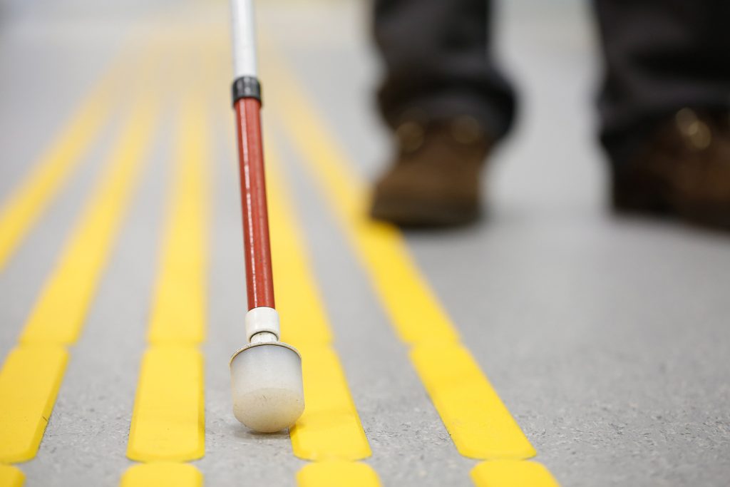 Person with visual impairment following tactile paving across the sidewalk.