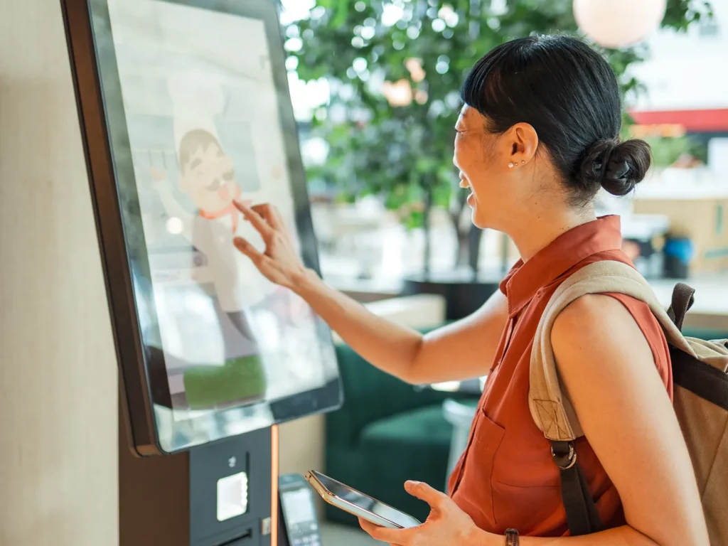Young woman using a self-ordering kiosk in a restaurant.